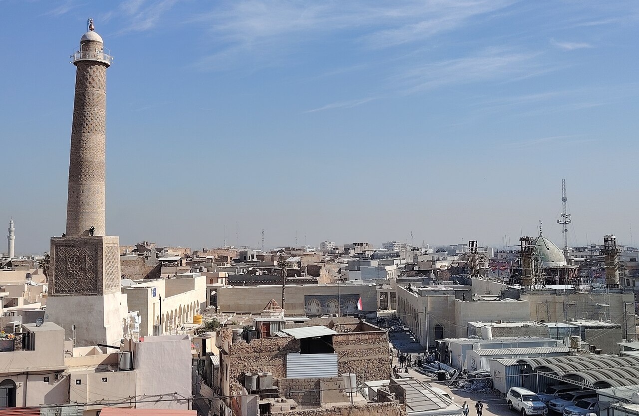 Historic photograph of the Al-Hadba minaret of the Great Mosque of al-Nuri, leaning over the rooftops of the Old City of Mosul.